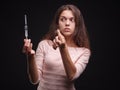 Woman holding a syringe and tuft of hair on a black background. Addiction and sickness symptoms. Hair treatment concept.