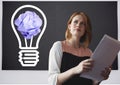 Woman holding tablet standing next to light bulb with crumpled paper ball in front of blackboard Royalty Free Stock Photo
