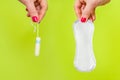 Woman holding tampon and sanitary napkin in hands