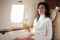 Woman holding tasty cocktail in private jet