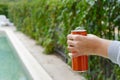 Woman holding tasty open canned beverage near swimming pool outdoors, closeup. Space for text