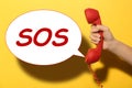 Woman holding telephone handset on yellow background, closeup. Emergency SOS call Royalty Free Stock Photo