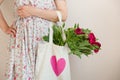 Woman holding a textile bag with beautiful bunch of red peonies. Girl's hands with bag full of peony flowers. Summer Royalty Free Stock Photo