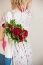 Woman holding a textile bag with beautiful bunch of red peonies. Girl`s hands with bag full of peony flowers. Summer Royalty Free Stock Photo