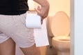 Woman holding toilet paper and using bathroom in morning Royalty Free Stock Photo