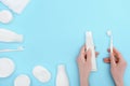 Woman holding toothbrush and toothpaste isolated on blue with cosmetic cream and lotion bottles Royalty Free Stock Photo