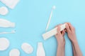 Woman holding toothbrush and toothpaste isolated on blue with cosmetic cream and lotion bottles Royalty Free Stock Photo