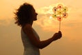 Woman holding toy whirligig at sunset