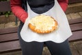 Woman holding a traditional langosh in her hands, sitting on a park bench, Langos, a deep fried pastry popular in Eastern Europe,