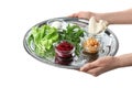 Woman holding traditional Passover Pesach Seder plate plate with symbolic meal on white background