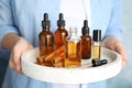 Woman holding tray with different bottles of essential oils