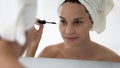 Woman holding tube applying black mascara on eyelashes closeup image