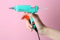 Woman holding turquoise glue gun with stick on pink background, closeup Royalty Free Stock Photo