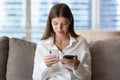 Woman holding two modern smart phones seated on couch Royalty Free Stock Photo