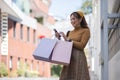 A woman is holding two pink shopping bags and looking at her cell phone Royalty Free Stock Photo