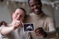 Woman holding ultrasound image of her baby showing her husband details on it. Royalty Free Stock Photo