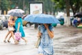 A woman is holding an umbrella during heavy rain in the city and talking on the phone