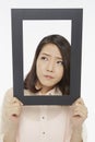 Woman holding up a black picture frame, looking sad Royalty Free Stock Photo