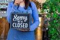 Woman Holding up a shop sign saying: sorry we are cloded