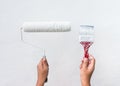 Woman holding up used paint brush and roller with white paint and white wall background Royalty Free Stock Photo