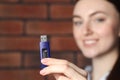 Woman holding usb flash drive near brick wall, focus on hand Royalty Free Stock Photo