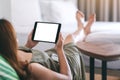 A woman holding and using tablet pc with blank screen horizontally while relaxing and lying on the bed Royalty Free Stock Photo