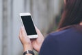 A woman holding and using white smart phone with blank black screen in outdoor and old white concrete wall background Royalty Free Stock Photo