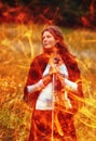 Woman holding a violin in a field, surrounded by flames