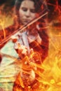 Woman holding a violin in a field, surrounded by flames