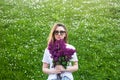 Woman holding a vivid bunch of lilac flowers against summer green floral background