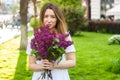 Woman holding a vivid bunch of lilac flowers in spring park