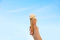 Woman holding waffle cone with delicious ice cream against blue sky on city street, closeup Royalty Free Stock Photo