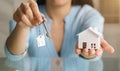 Woman holding white house model and house key in hand.Mortgage loan approval home loan and insurance concept