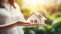 Woman holding white house model and house key in hand.Mortgage loan approval home loan and insurance concept