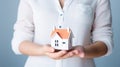 Woman holding white house model and house key in hand.Mortgage loan approval home loan and insurance concept