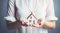 Woman holding white house model and house key in hand.Mortgage loan approval home loan and insurance concept