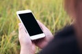 A woman holding white mobile phone with blank black desktop screen with blur green nature background Royalty Free Stock Photo