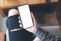 A woman holding white mobile phone with blank black desktop screen on thigh in cafe Royalty Free Stock Photo