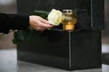 Woman holding white rose near granite tombstone with candle outdoors, closeup. Funeral ceremony Royalty Free Stock Photo