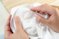 Woman holding white shirt with blank clothing label indoors, closeup Royalty Free Stock Photo