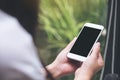 A woman holding white smart phone with blank black desktop screen with blur green nature background Royalty Free Stock Photo