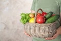 Woman holding wicker basket with ripe fruits and vegetables on color background, closeup Royalty Free Stock Photo