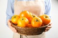 Woman holding wicker bowl of yellow tomatoes on light background, closeup Royalty Free Stock Photo