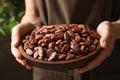 Woman holding wooden bowl of cocoa beans, closeup Royalty Free Stock Photo