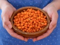 Woman holding wooden bowl full of frozen ripe sea buckthorn berries in her hands Royalty Free Stock Photo