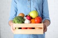 Woman holding wooden crate with fruits and vegetables at white brick wall Royalty Free Stock Photo