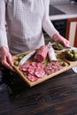 Woman holding wooden cutting board with Traditional Spanish fuet salami sausage at domestic kitchen Royalty Free Stock Photo