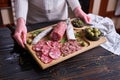 Woman holding wooden cutting board with Traditional Spanish fuet salami sausage at domestic kitchen Royalty Free Stock Photo