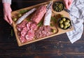 Woman holding wooden cutting board with Traditional Spanish fuet salami sausage at domestic kitchen Royalty Free Stock Photo