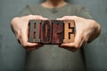 Woman holding the word `hope` made of wooden typographic letters